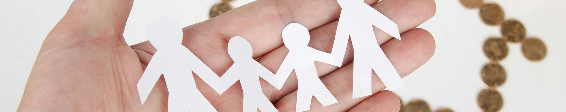 Hand holding white paper cutouts of two adults and two children