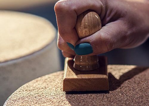 Close up of craftswoman hands stamps trademark on her product